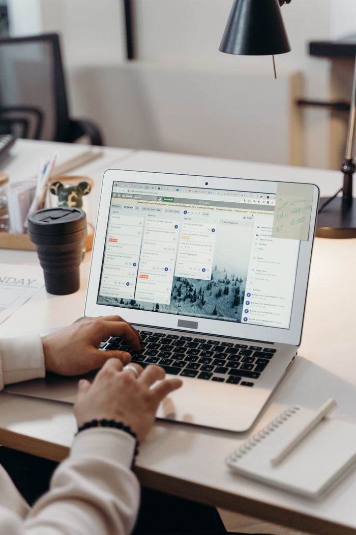Mastering the First Impression: Your intriguing post title goes here Hands typing on a laptop in a modern office setting with notes and task management software visible on the screen.